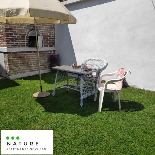 a patio table and two chairs under an umbrella at Just nature in Novi Sad