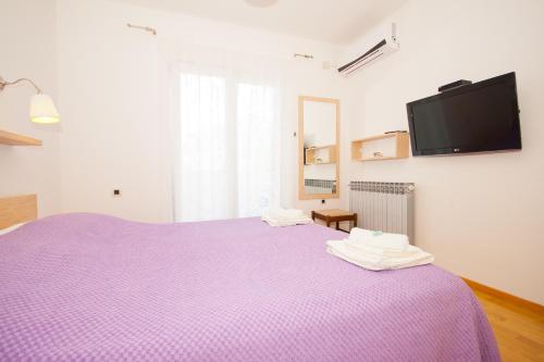 a bedroom with a purple bed with a tv on the wall at Apartment Zvone in Baška