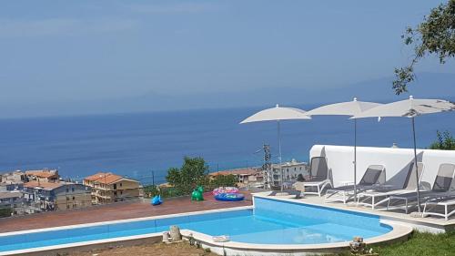 - une piscine avec des chaises longues et des parasols dans l'établissement Appartamenti Borgo Panoramico N 4, à Tropea