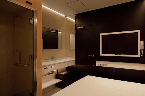 baño con cama, lavabo y TV en hotel min., en Tokio