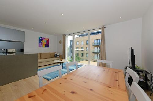 a living room with a wooden table and a kitchen at Grand Apartments Kew Gardens in London