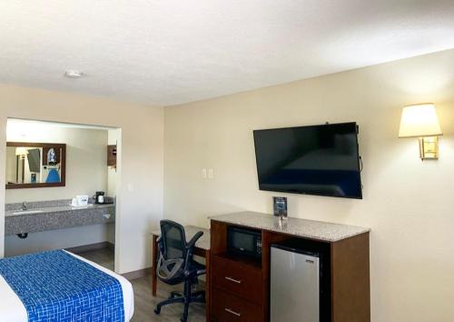 a hotel room with a bed and a flat screen tv at Travelodge by Wyndham Cedar City in Cedar City