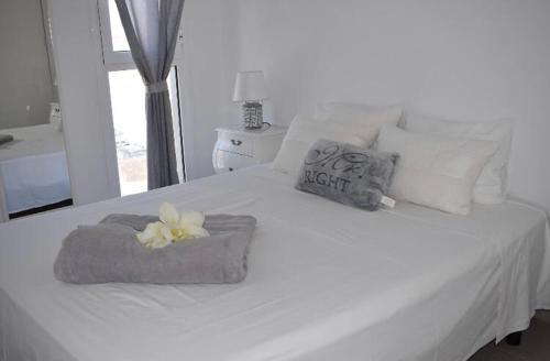 a white bed with a towel and flowers on it at APARTAMENTO MAGNIFIK in Corralejo