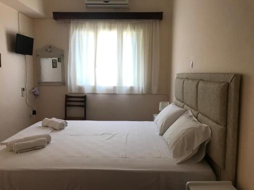 - une chambre avec un grand lit blanc et une fenêtre dans l'établissement Natalia Studios, à Poros