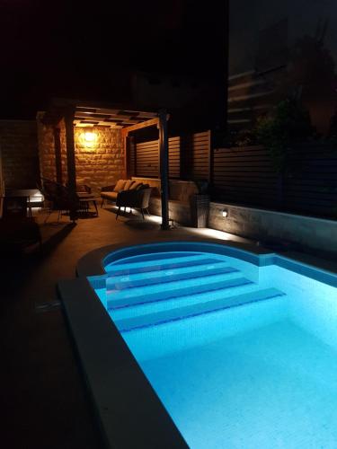 a swimming pool lit up at night at Villa Kozina in Podstrana