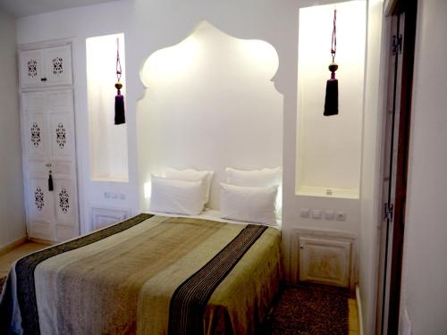 a bedroom with a bed with white walls and two windows at Dar Tifrouine in Lalla Takerkoust
