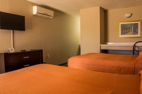 a hotel room with two beds and a flat screen tv at BONITTO INN® Tampico Altamira in Tampico