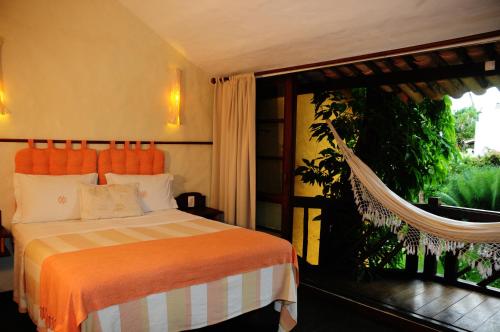a bedroom with a bed and a large window at Pousada Dos Artistas in Praia do Forte