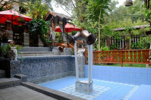 uma fonte em frente a um edifício com um guarda-chuva em Badjoeri Ethnic Wooden Homestay em Bandung