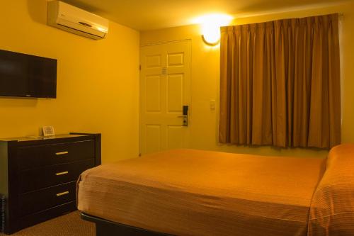 a bedroom with a bed and a dresser and a television at BONITTO INN® Tampico Aeropuerto in Tampico
