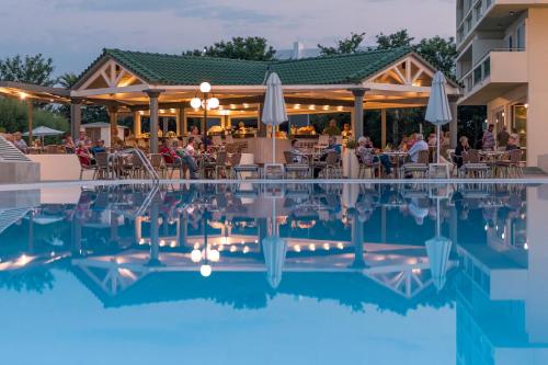 a swimming pool with people sitting at a restaurant at Apollo Beach in Faliraki
