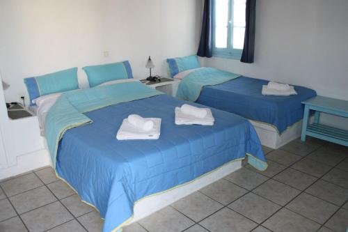 two beds in a room with blue sheets and towels at Ampelos in Chora Folegandros