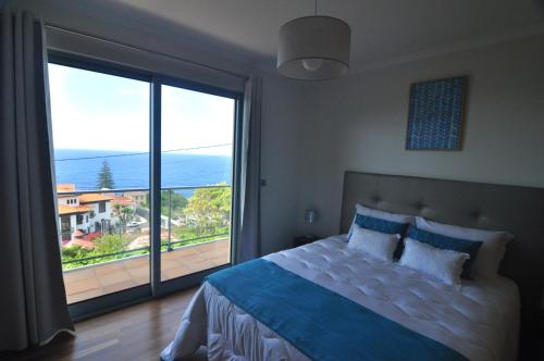 a bedroom with a large bed and a large window at Ponte House in Porto Moniz