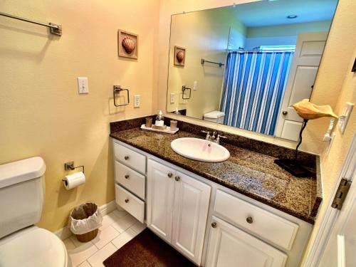 a bathroom with a sink and a toilet and a mirror at Mi Casa Del Mar Home in Caplen