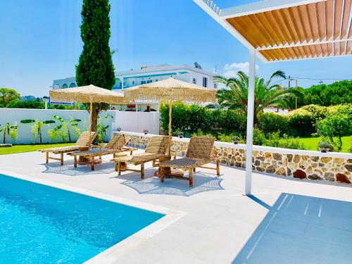 a pool with chairs and umbrellas next to a pool at Mythos Luxury Villa in Faliraki