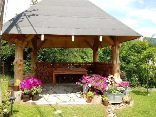 a wooden gazebo with a table and flowers at Dom Gościnny BIERWIONO in Cisna