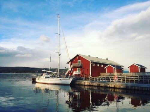 a sailboat docked at a dock in front of a red building at Kajkanten Restaurang B&B in Köpmanholmen