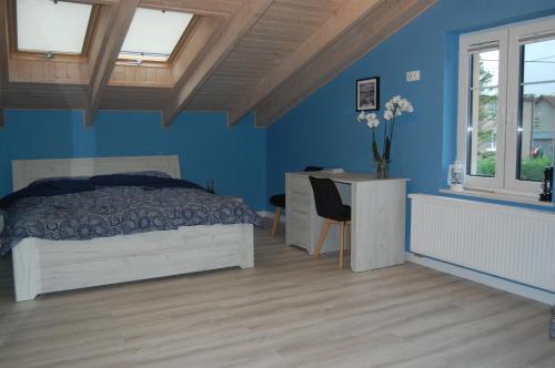 a bedroom with blue walls and a bed and a desk at Apartament Rybacka12 in Rewa