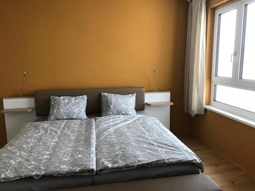 1 dormitorio con 1 cama con 2 almohadas y ventana en Spacious, Modern 1-bdrm Apt near VIC & Austria Ctr, en Viena