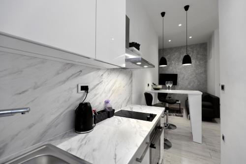 a white kitchen with a sink and a desk at VenaRi apartments, Rijeka in Rijeka