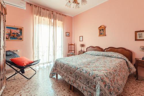 a bedroom with a bed and a chair and a window at Theokles Apartment in Taormina