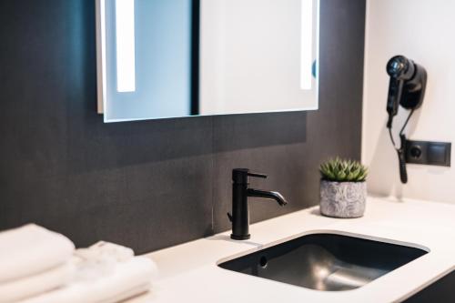 a bathroom sink with a faucet and a mirror at Maestro Design Hotel in Liepāja
