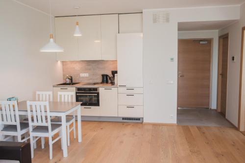 eine Küche mit weißen Schränken sowie einem Tisch und Stühlen in der Unterkunft Tiiru beachside apartment in Pärnu