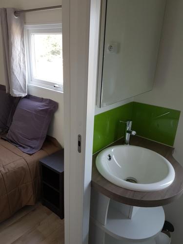 La salle de bains est pourvue d'un lavabo, d'une fenêtre et d'un lit. dans l'établissement Village Guerzaille, à Saint-Caradec
