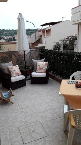 a patio with two chairs and an umbrella at 4 stagioni in Villasimius