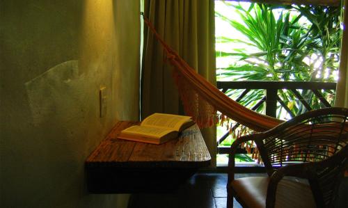 a room with a hammock and a book on a table at Pousada Dos Artistas in Praia do Forte