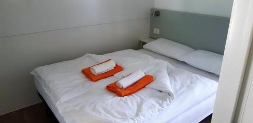 a small bed with two orange pillows on it at Mobile Homes and Apartment - Terme Čatež in Čatež ob Savi