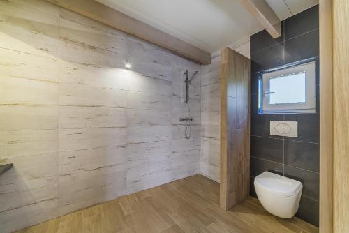 a bathroom with a toilet and wooden walls at Nowa Dana Ośrodek Wypoczynkowy in Łebcz