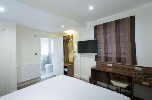a bedroom with a bed and a desk and a television at Heathrow-Windsor Guest House in Slough