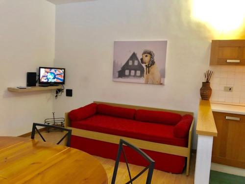 ein Wohnzimmer mit einem roten Sofa und einem TV in der Unterkunft Appartamento AB in Passo San Pellegrino