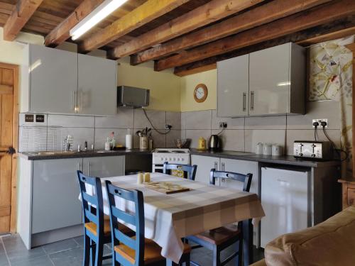 a kitchen with a table and chairs in a kitchen at Row Farm Cottage in Millom