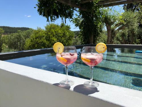 two wine glasses sitting on a ledge next to a swimming pool at Casa da Praia do Ribatejo in Praia do Ribatejo