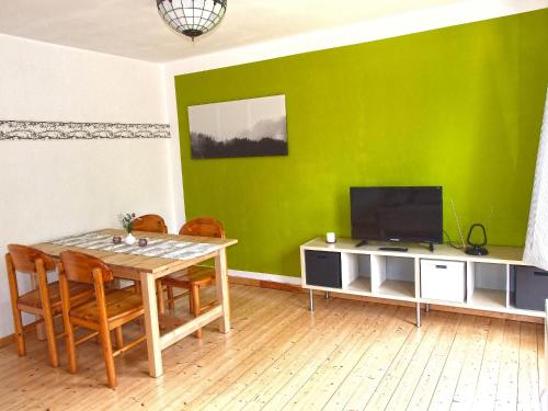 a dining room with a table and a green wall at Ferienwohnung Goslar - Georgenberg / Entspannen im Harz / Mittendrin in Goslar