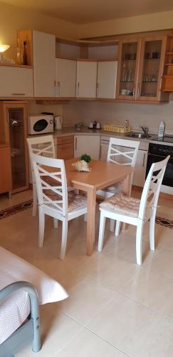 a kitchen with a wooden table and white chairs at App LOLLY in Selce