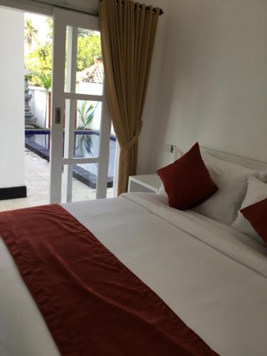 a bedroom with a large white bed with red pillows at Queen Guest house tulamben in Tulamben