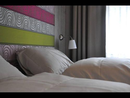 a bedroom with a bed with white pillows and a lamp at Herberg 't Voshoes in Mechelen