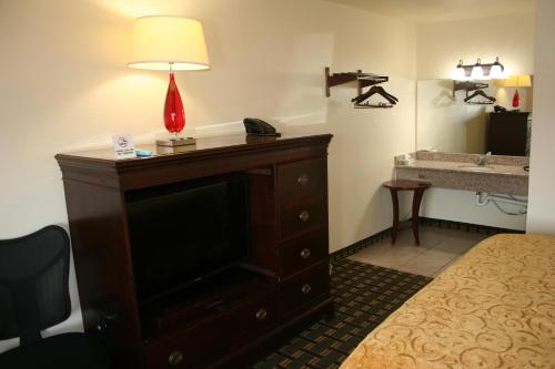 a hotel room with a television and a lamp on a dresser at Scottish Inns Weatherford in Weatherford