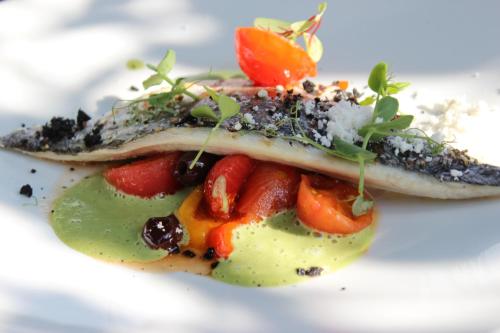a piece of fish with fruit on a white plate at Cozy floating boatlodge "Maastricht". in Maastricht