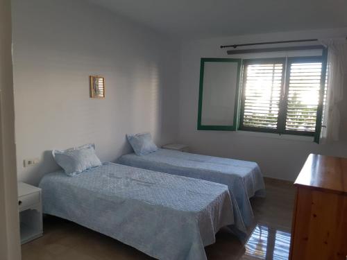 2 camas en una habitación blanca con ventana en Apartamentos Tahiche, en Costa Teguise