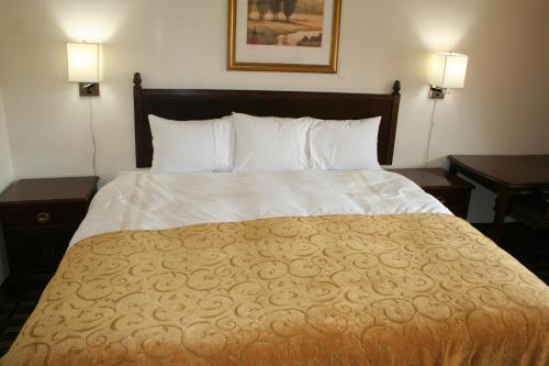 a bed in a hotel room with two tables and two lamps at Scottish Inns Weatherford in Weatherford