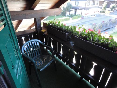 a chair sitting on a balcony with plants at Hotel Garni Alpenruh in Lenk