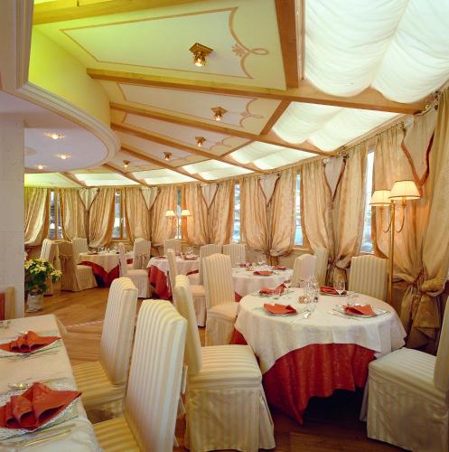 a dining room with white tables and white chairs at Hotel Patrizia Dolomites Glamour in Moena