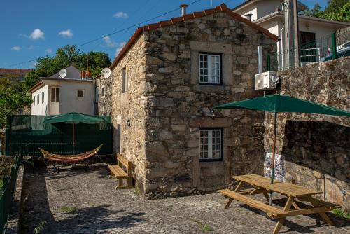 a stone building with a table and a green umbrella at Casa dos Cortes in Sever do Vouga
