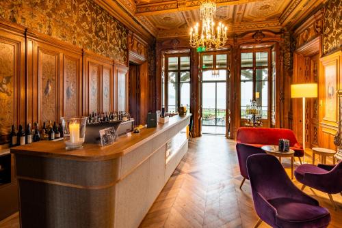 a large room with a bar with purple chairs at Schloss Schadau - Swiss Historic Hotel in Thun