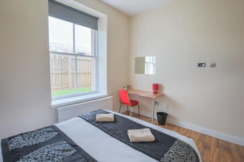 a bedroom with a bed and a desk and a window at Stylish Modern 4 Bed Apartment in Edinburgh