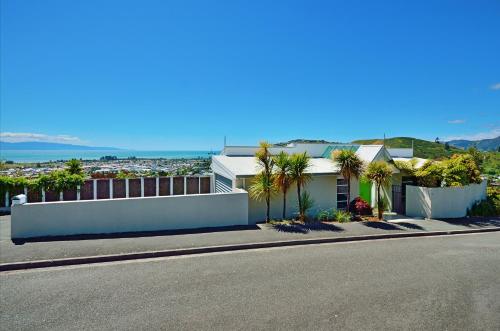 a house on the side of a street with palm trees at Aporo Nelson Holiday Home in Nelson
